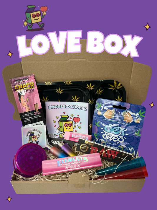 Visuel promotionnel "Love Box" Saint-Valentin par SmokeboxShop sur fond violet fun. Présentation complète du pack cadeau : accessoires de roulage premium (Elements, RAW, grinder), blunts et gummies aphrodisiaques Sex Bites. Tout pour une expérience Fumeur unique à retrouver sur smokeboxshop.fr.